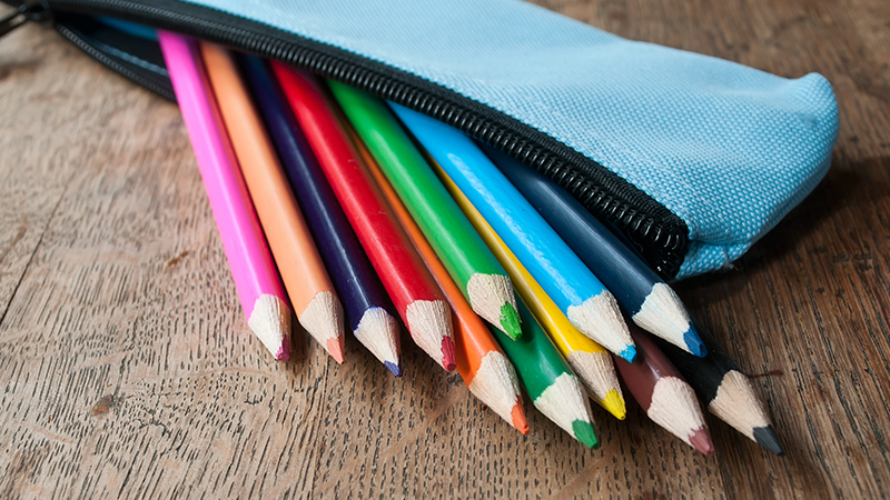 A pack of multicolored pencils lying on a wooden table