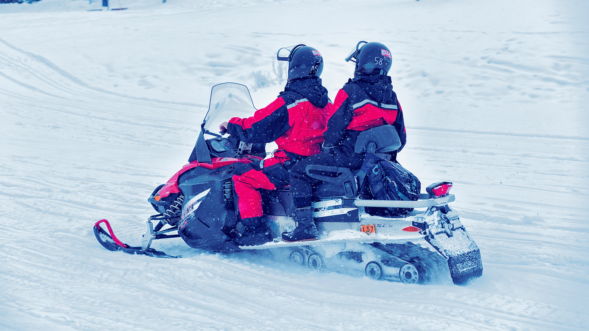 Couple riding snowmobile on frozen lake in winter