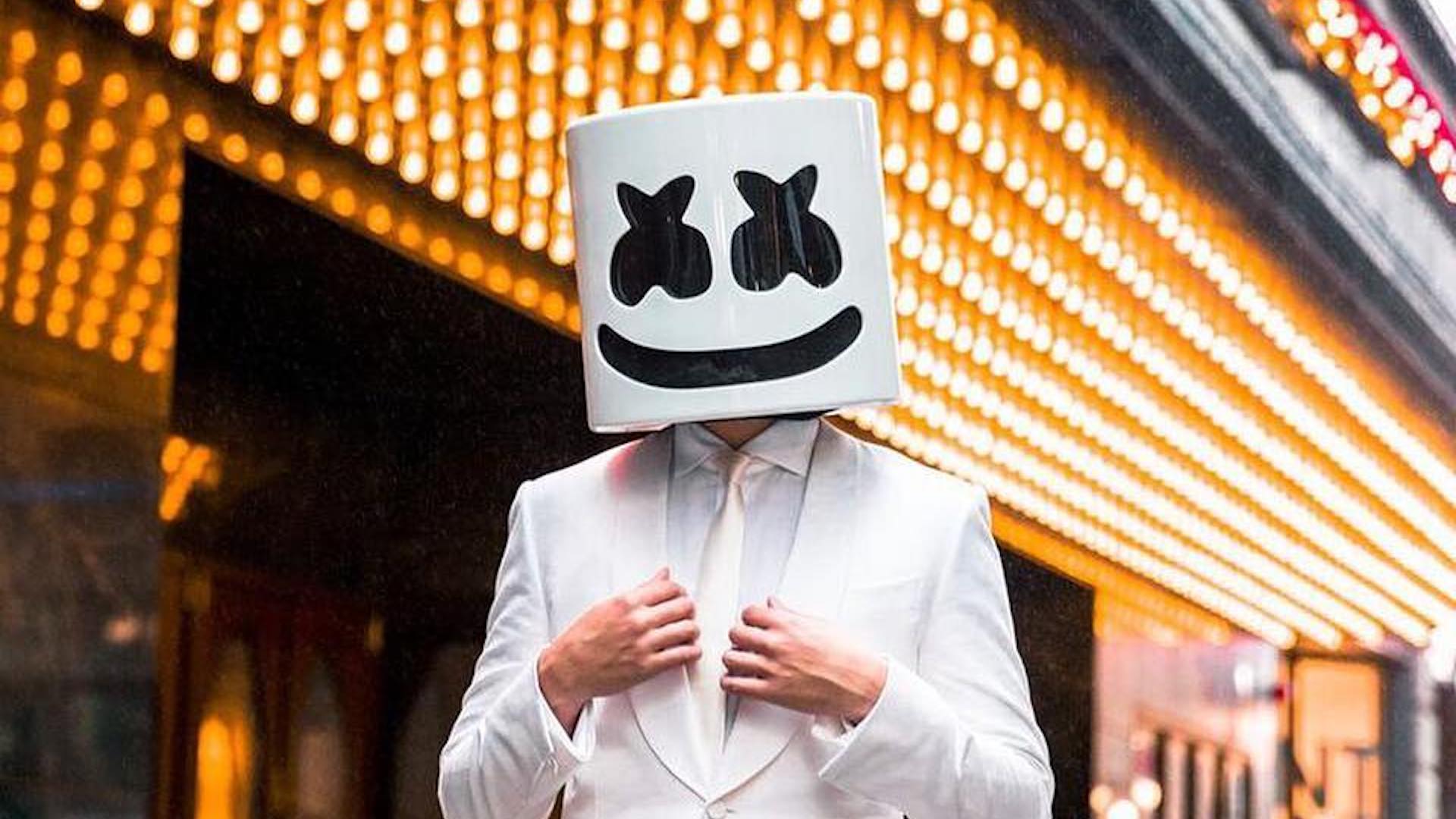 DJ Marshmello in a crisp white suit against lots of lights