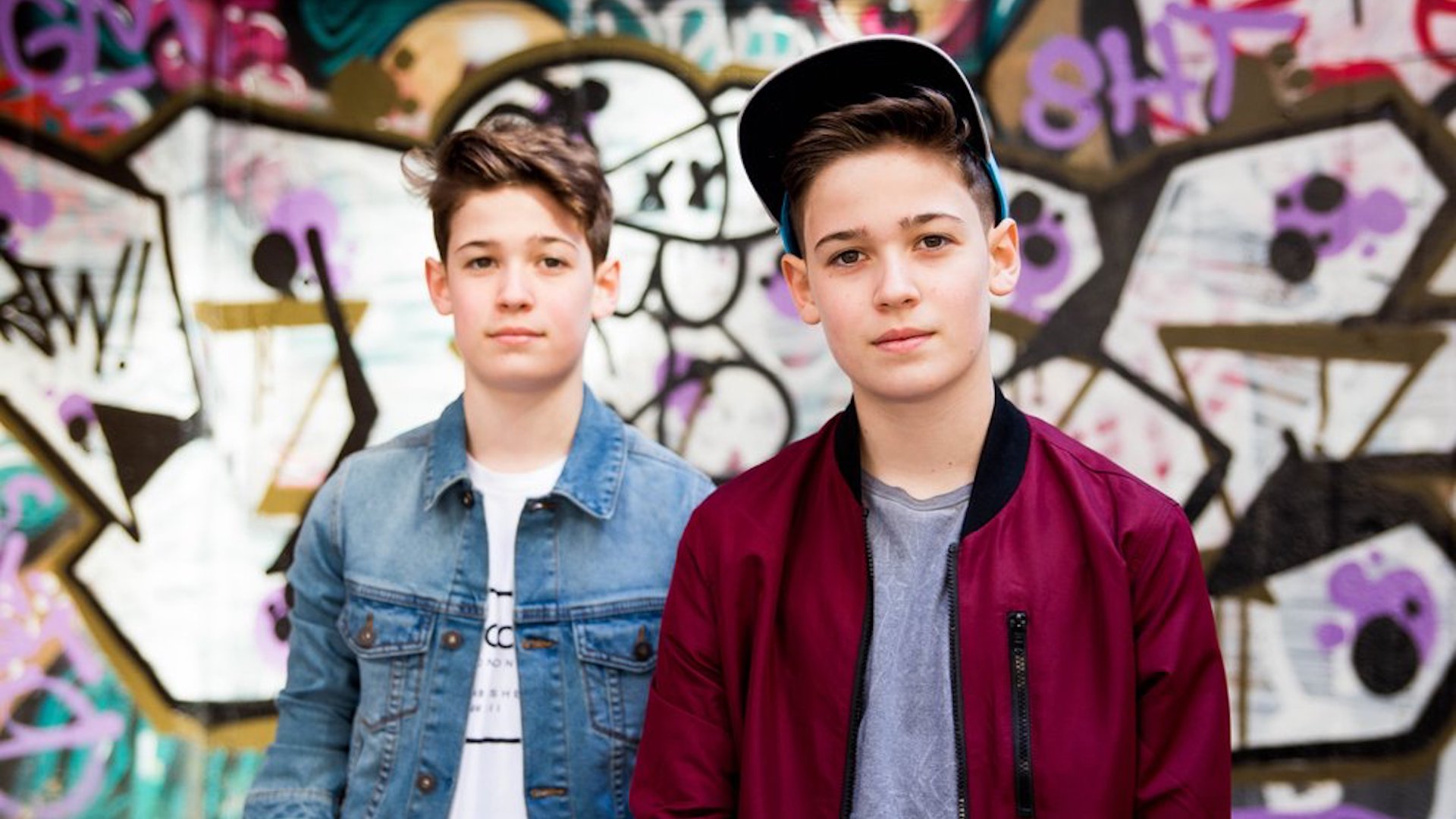 Max and Harvey stand in front of a graffiti wall