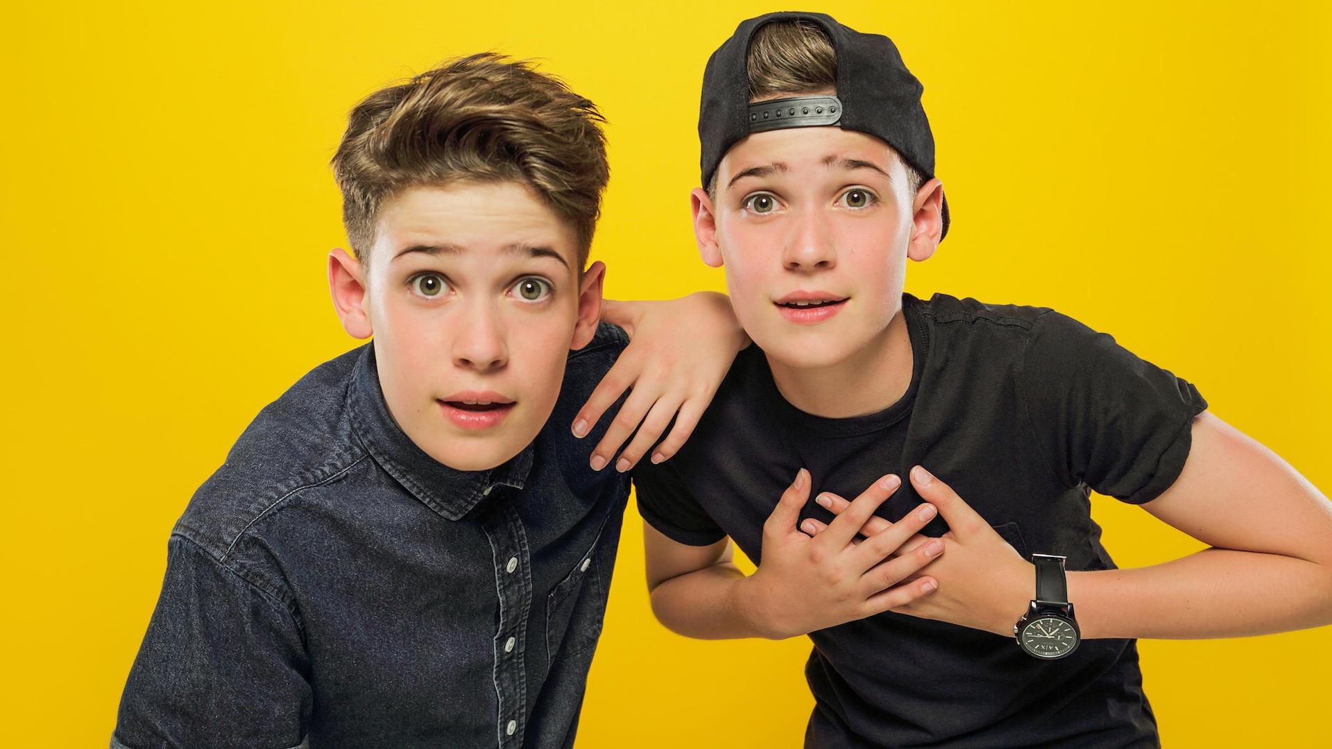 Max and Harvey dressed in black against a yellow background