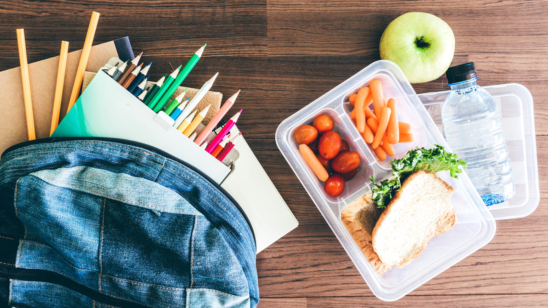 Lunch box with vegetables and slice of bread for a healthy school lunch on wooden table