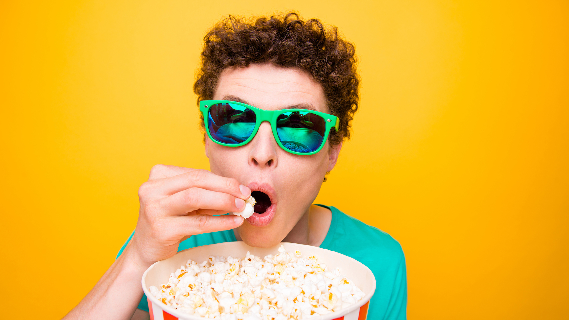 A person in sunglasses eating popcorn