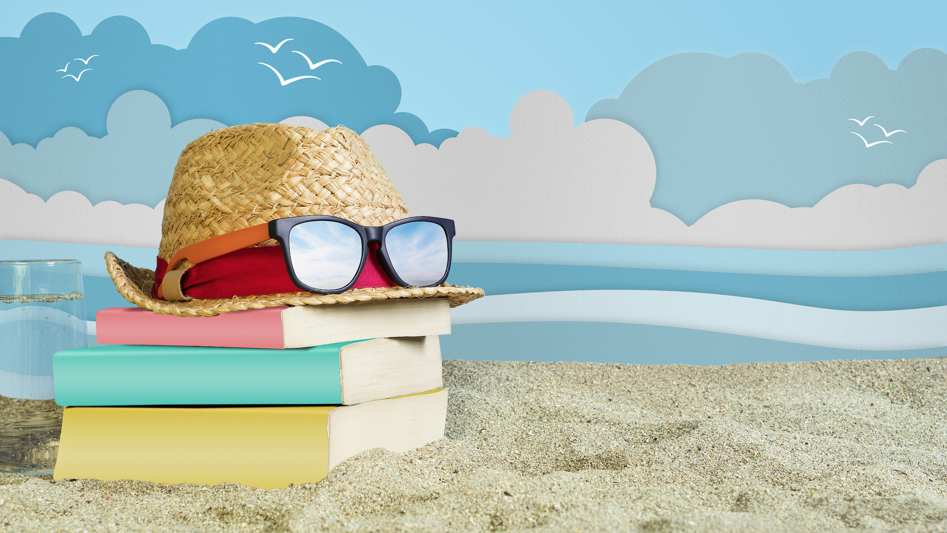 A pile of books on the beach... wearing a hat