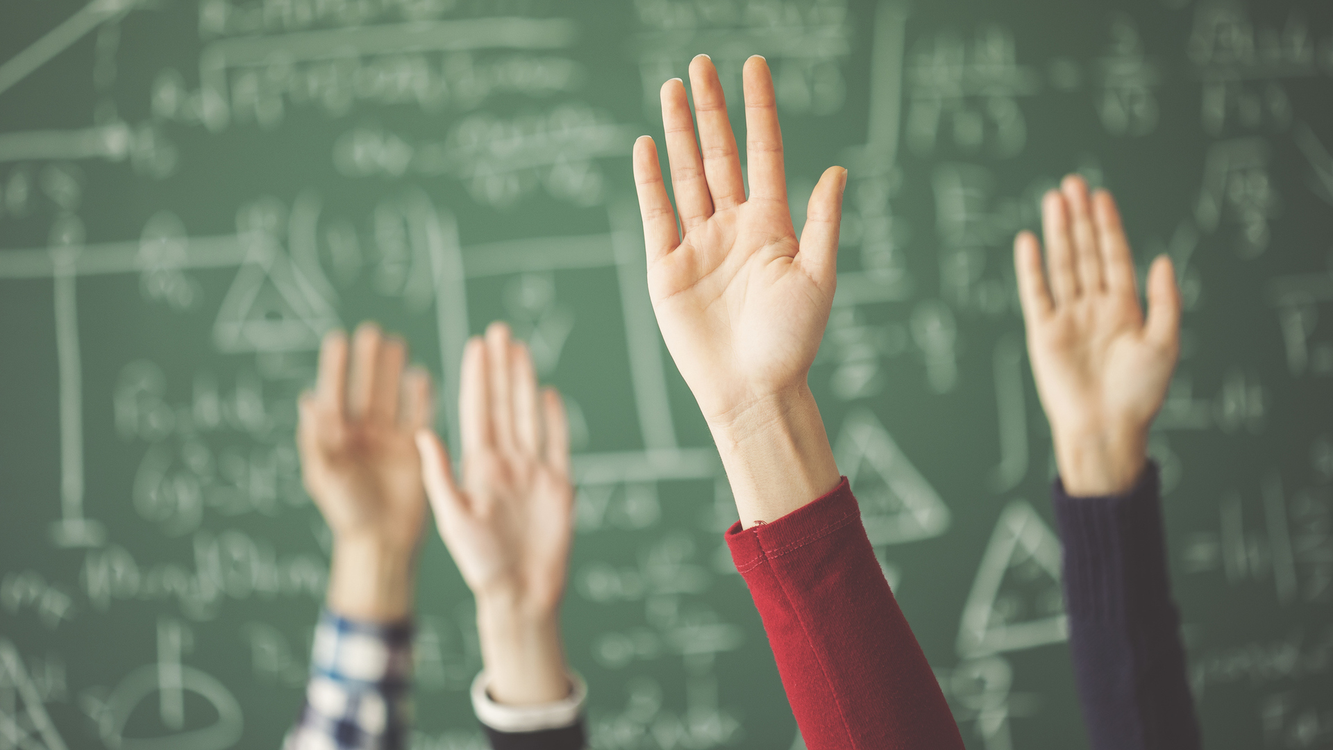 Students raising their hands in a maths lesson