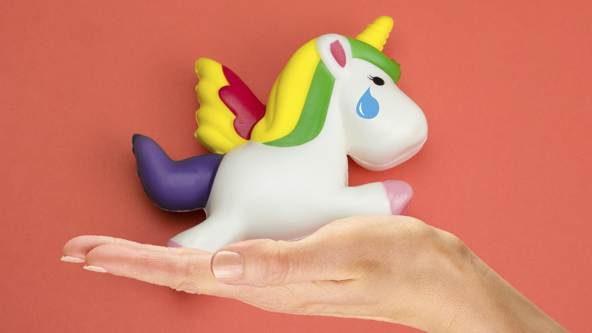 A unicorn squishy sits in the palm of someone's hand