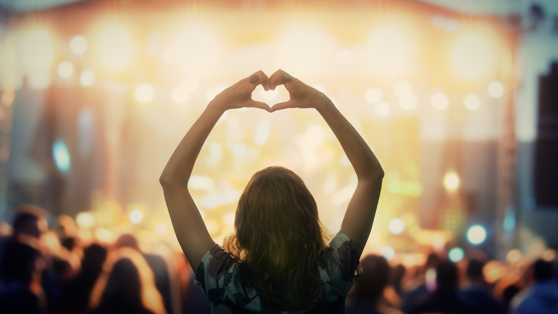 A person making a heart shape with their hands a pop concert