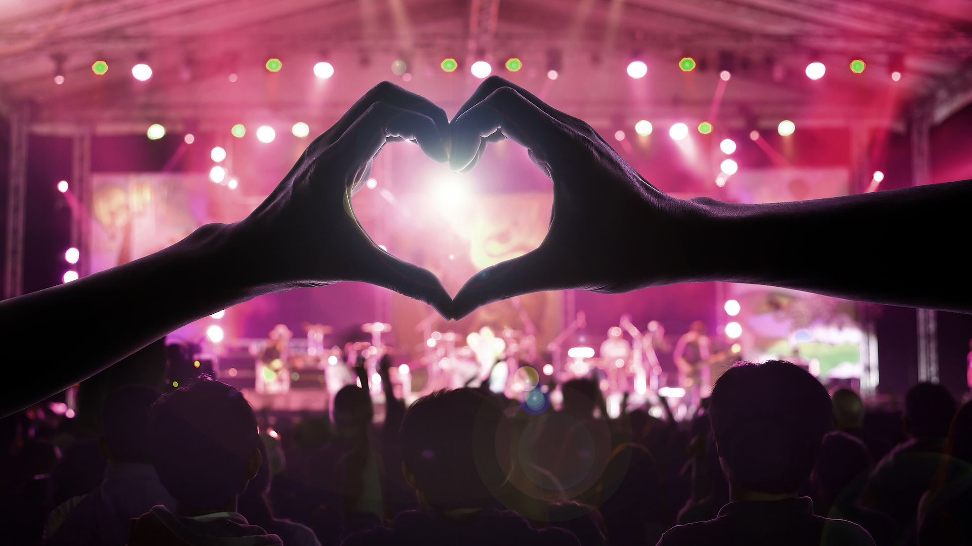 A pair of hands make a heart shape at a pop concert 