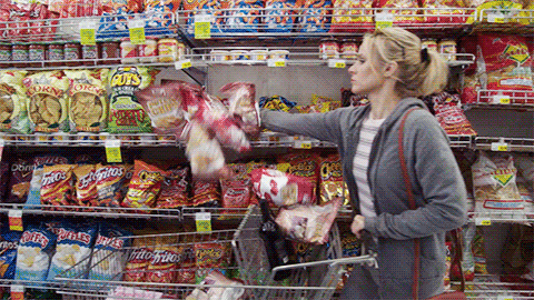 A woman putting lots of snacks into a trolley