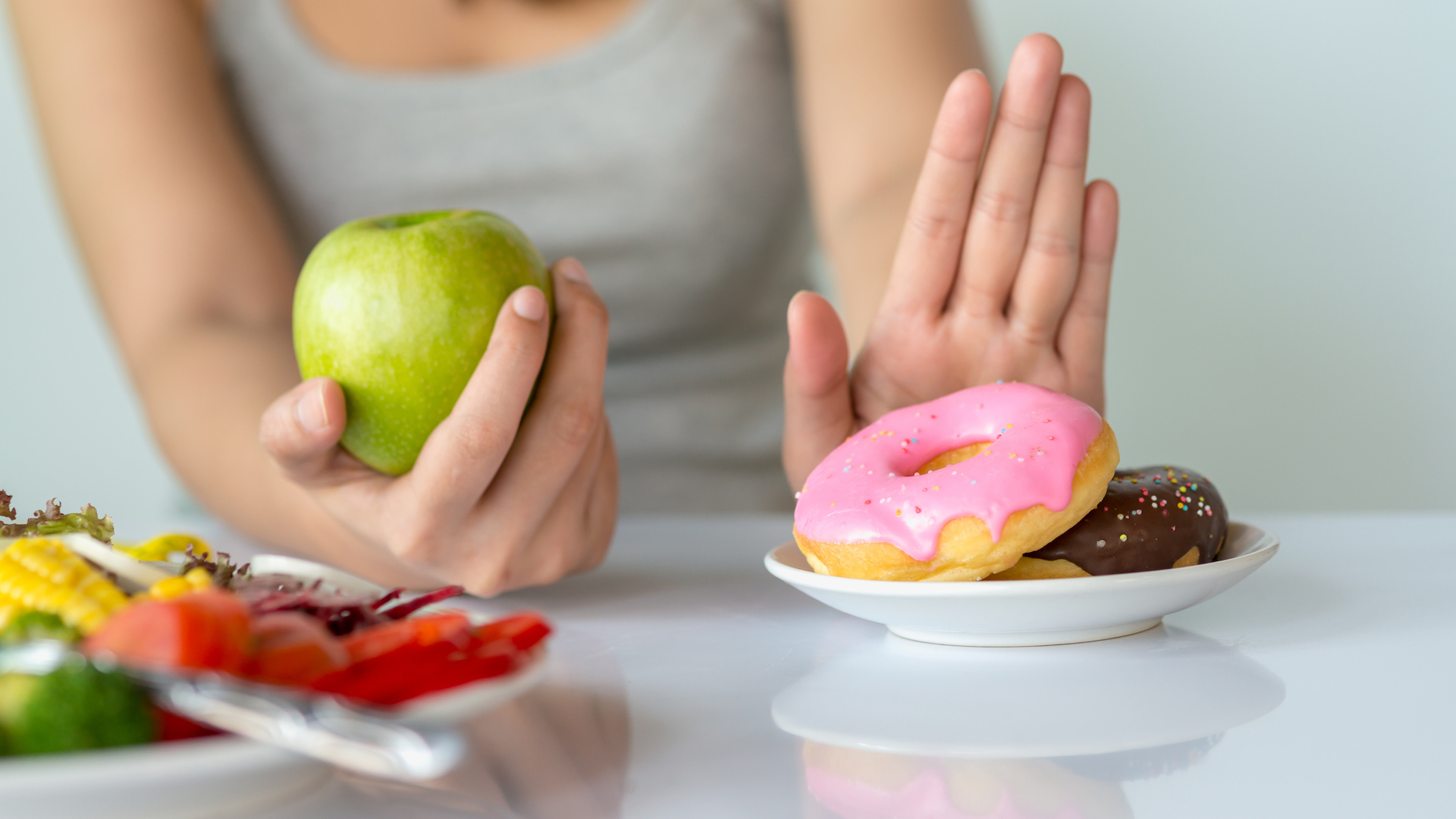 A person choosing an apple over a donut