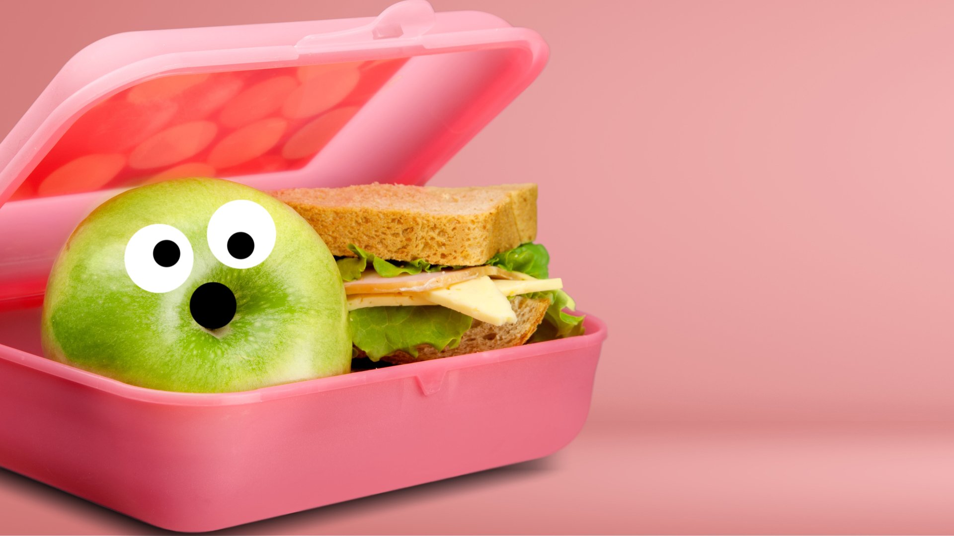 A packed lunch with a scared looking apple