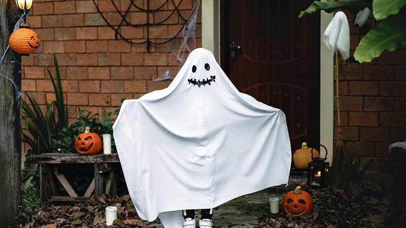 A white ghost in a garden surrounded by Halloween pumpkins