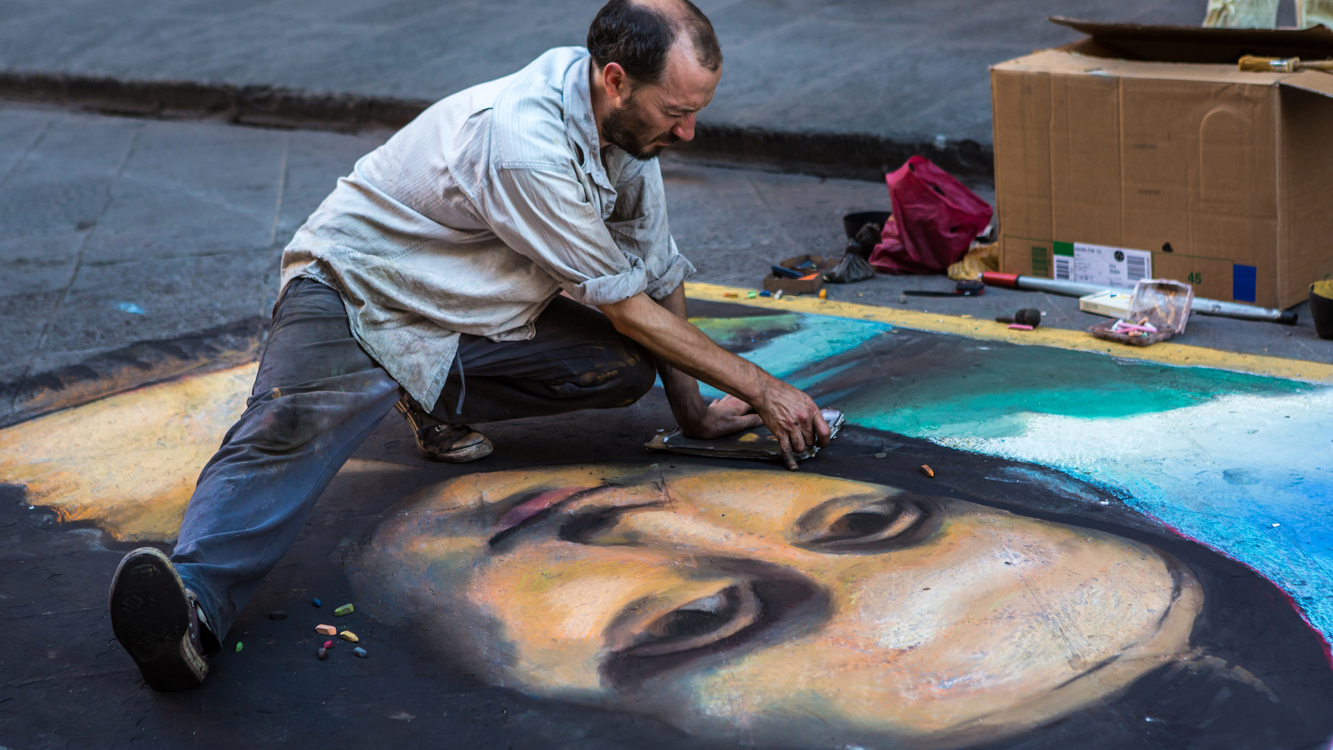 A street artist drawing on the pavement with chalk