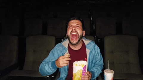 A man eating popcorn in a big cinema 