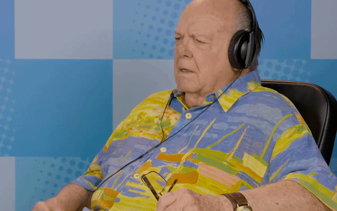 An elderly man rocking out wearing a big pair of headphones