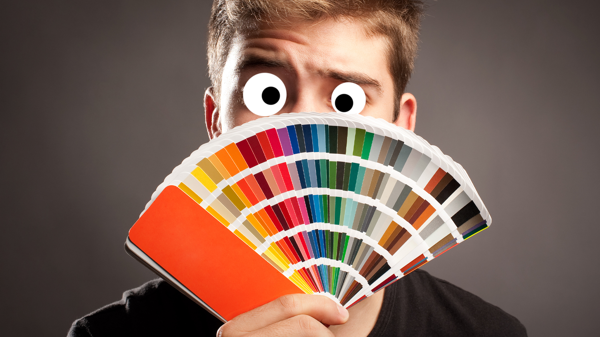 A man peeping behind a colour chart
