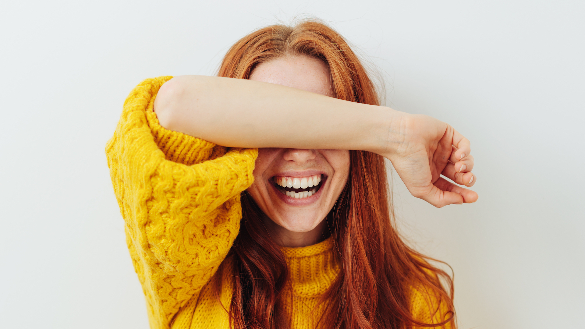 A woman covering her eyes and laughing 