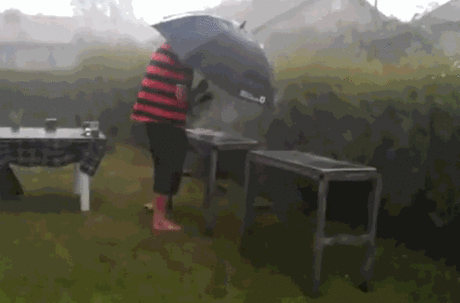 A person trying to cook a BBQ in the rain