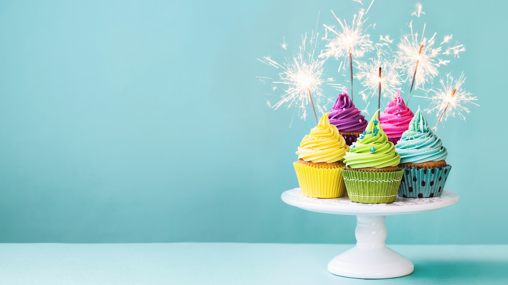 A plate of birthday cupcakes with sparklers 