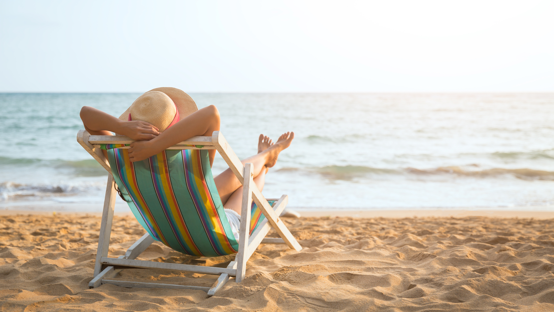 A person relaxing on a deckchair on a sandy beach