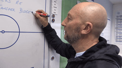 A football manager writes on a wipe board