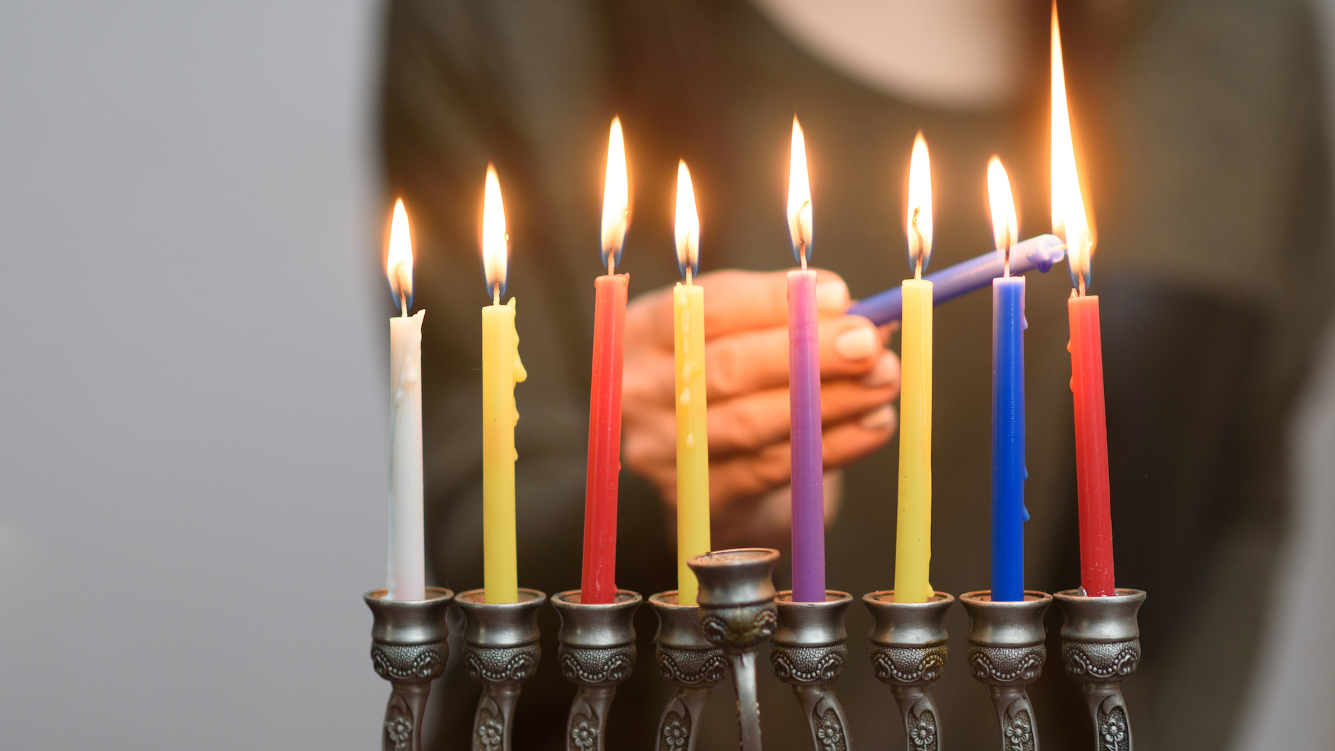 A Jewish Woman lighting Hanukkah candles in a menorah