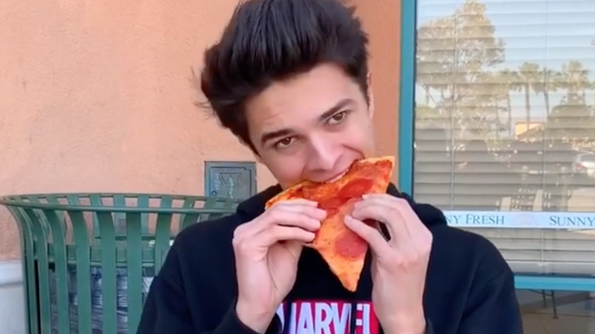 Brent eating a pepperoni pizza