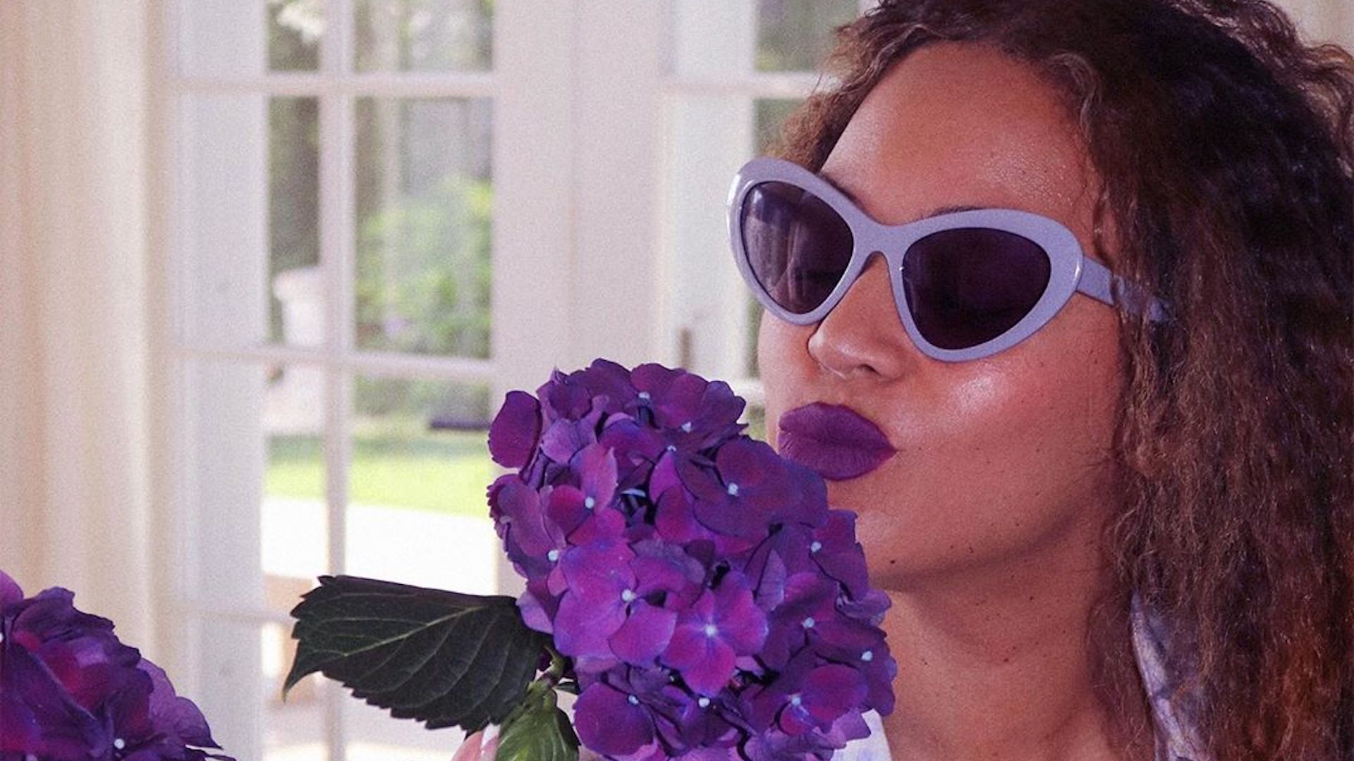 Beyonce smelling a large purple flower