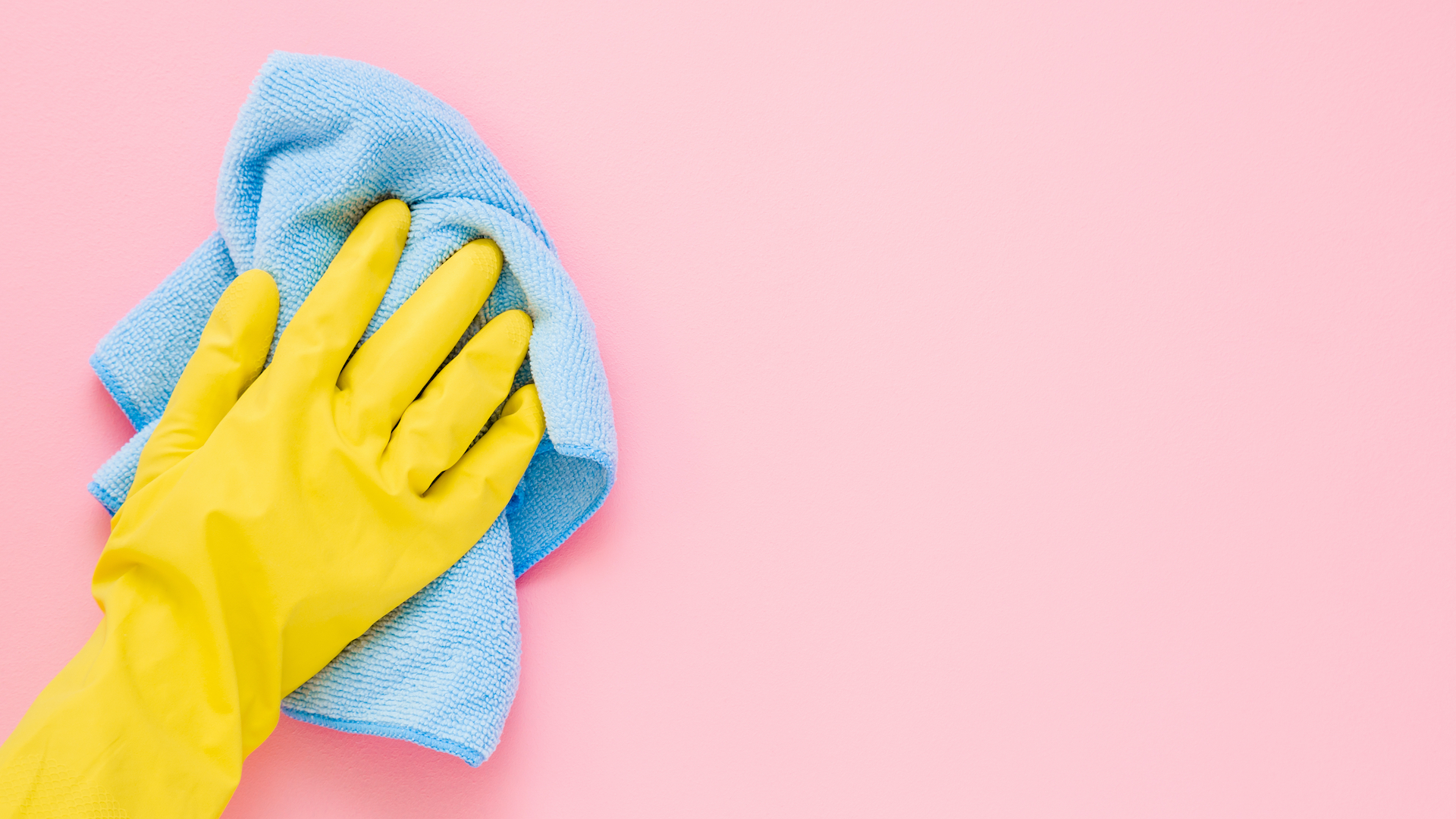 A hand cleaning a pink surface with a cloth