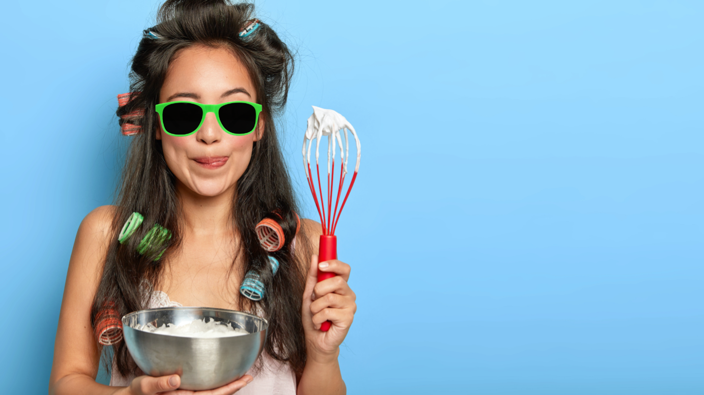 A woman holding a cake bowl and a whisk