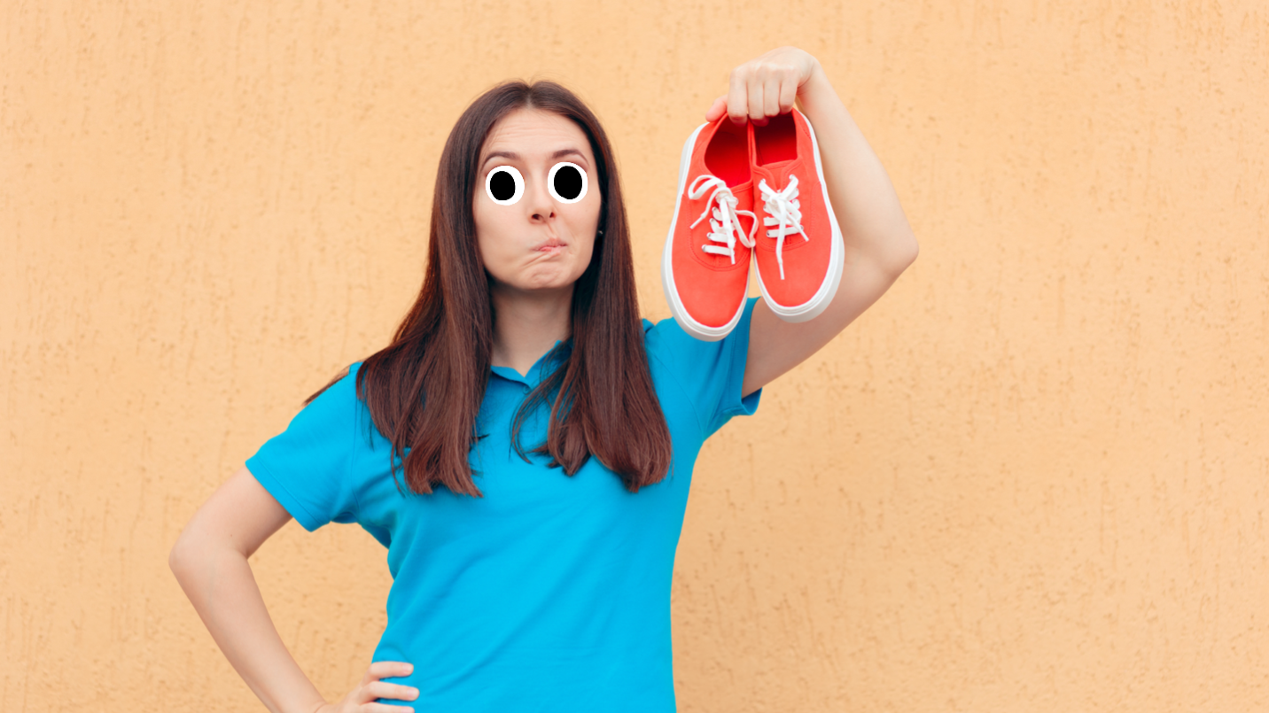 A woman holds up a pair of smelly trainers