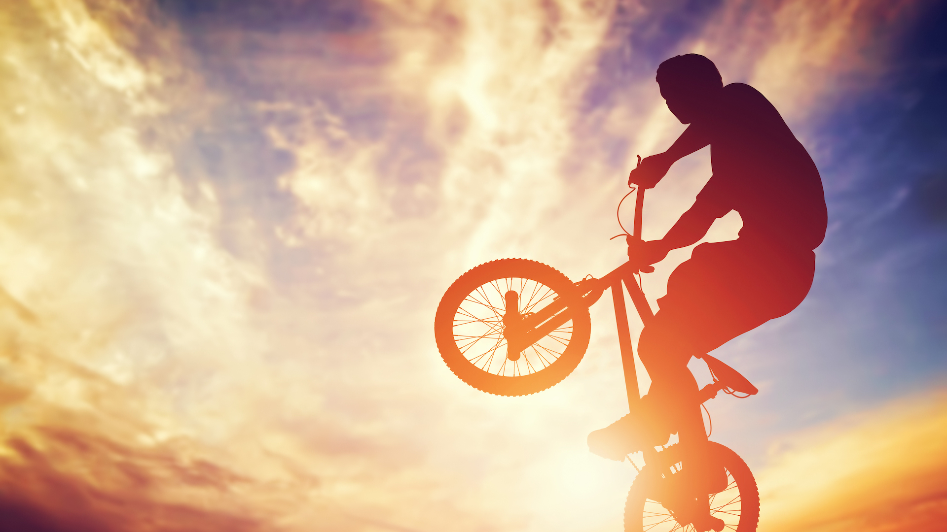 Man riding a BMX bike against the sunset