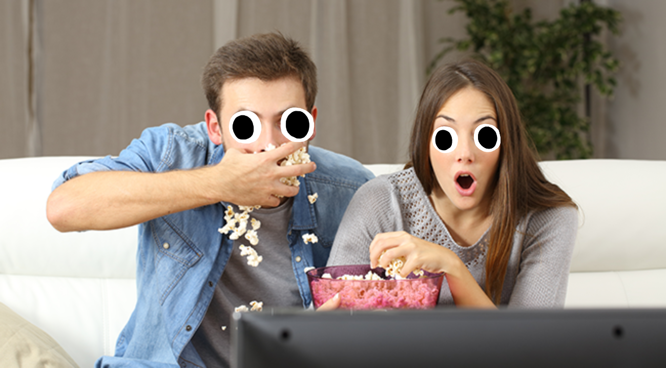 Man and woman watching tv and eating popcorn