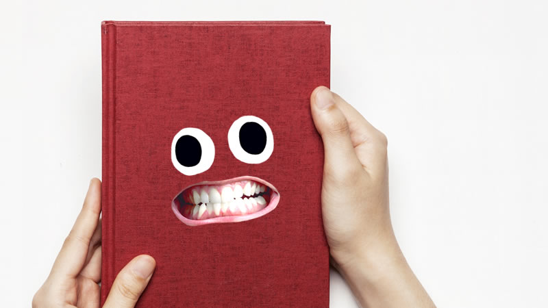 A person holding a grinning red book