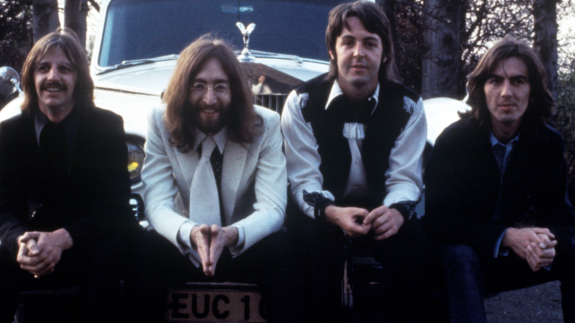 The Beatles sitting on a car