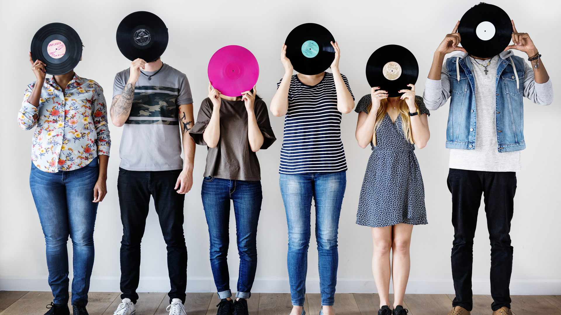 A line of people holding records up to their faces