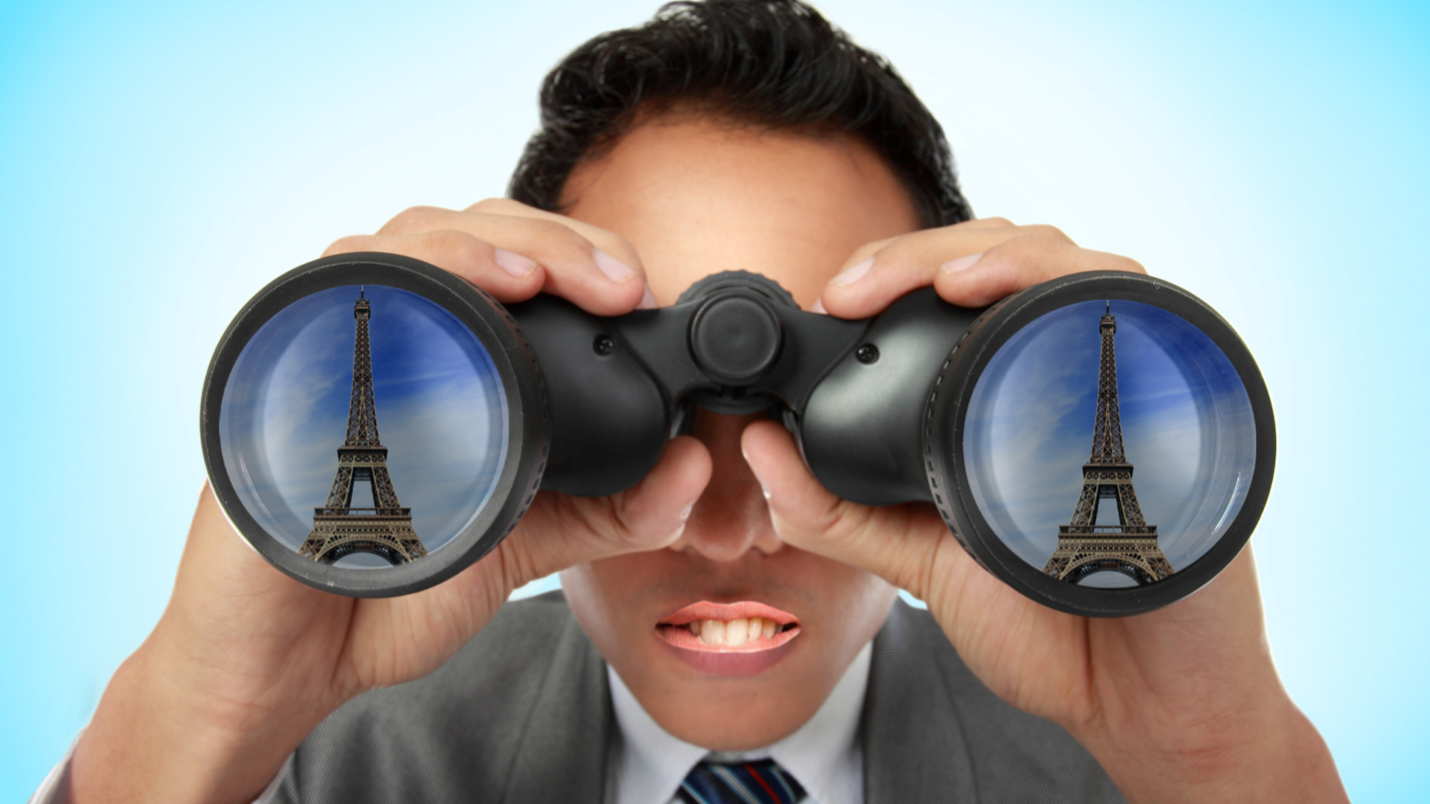 A man looking at the Eiffel Tower through a pair of binoculars