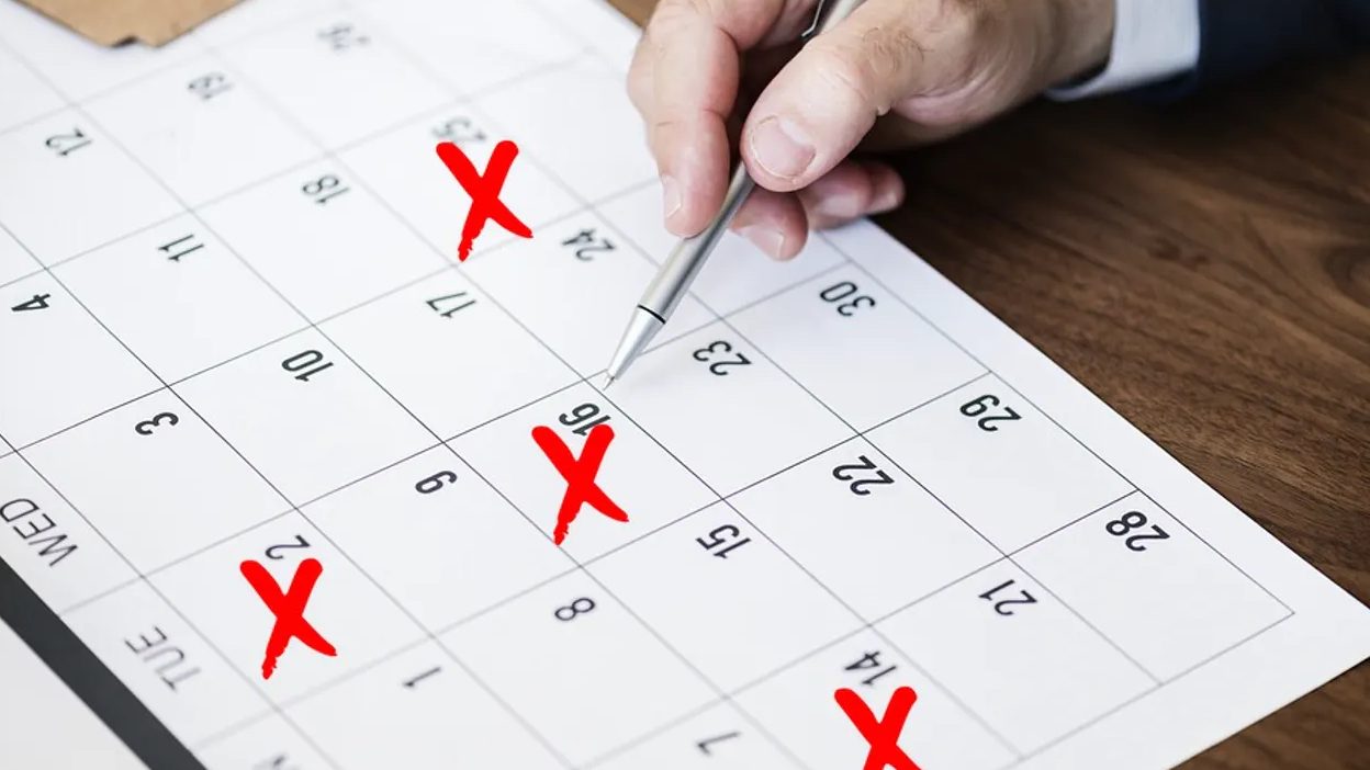 A person marking important dates on their wall calendar